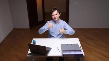 Office worker gesturing thumbs up at desk with laptop and files video