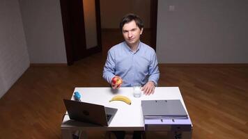 Office worker showing an apple during work break with healthy food on desk video