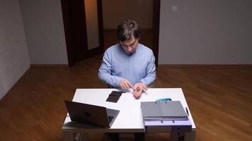 Office worker counting remaining coins at desk with laptop and files video