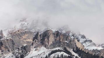 Snow covered peaks of the Dolomite mountains near Cortina, with mist and clouds, captured in a slow, sweeping motion over rugged terrain. video
