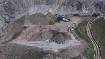 Aerial view of a mining site in the Alps with machinery, vehicles, and excavated earth. Motion includes machinery and vehicles in operation. video