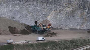 Aerial view of a mining site in the Alps with machinery processing minerals, large material piles, utility vehicles, and rugged mountainous terrain. video