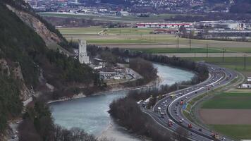 Antenne Aussicht von ein Bergbau Seite? ˅ im das Alpen, mit ein Fluss, ziehen um Fahrzeuge auf ein Autobahn, bewaldet Hügel, öffnen Felder, und ein entfernt Stadt. video