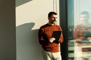 A man standing in front of a window with a tablet photo