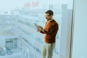 A man standing on a window sill with a tablet computer photo