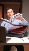 Office worker browsing documents at desk with laptop and binders video