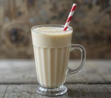 Creamy Beige Milkshake With Red Striped Straw On Rustic Wood photo