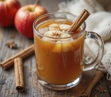 Warm Apple Cider with Cinnamon Sticks and Apples on Rustic Wooden photo