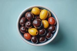 Colorful Variety of Olives Displayed in a Bowl on a Light Blue Surface photo