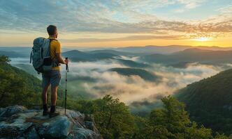 Hiker Gazes Over Misty Valley During Sunrise in the Mountains photo