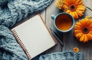 Cozy Workspace With Hot Tea, Open Notebook, and Vibrant Flowers on Wooden Table in a Serene Indoor Setting photo
