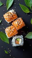 Delicious Sushi Rolls With Salmon and Avocado on a Black Background Decorated With Green Leaves photo