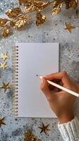 Hand Holding Pencil Over Blank Notebook With Gold Stars and Leaves for Creative Writing photo