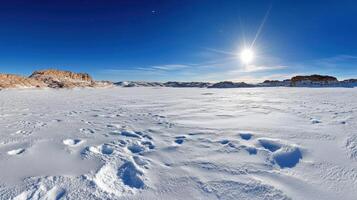 A panoramic view of a snowy landscape with the sun shining photo