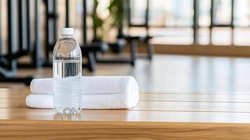 A bottle of water and towel on a wooden bench photo