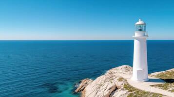 A white lighthouse on a rocky cliff overlooking the ocean photo