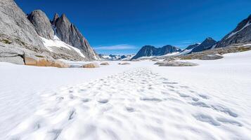 A snow covered mountain range with a trail in the middle photo