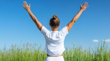 Woman with arms up in the air in a grassy field photo