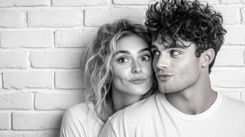 A man and woman are posing in front of a brick wall photo