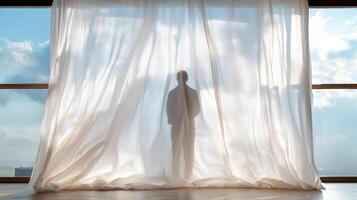 A man standing in front of a window with a curtain photo