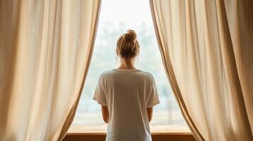 A woman standing in front of a window looking out photo