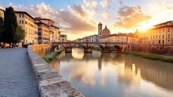 The sun is setting over a river in florence, italy photo
