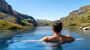 A man is floating in a lake with mountains in the background photo