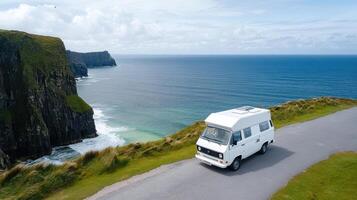 A camper van driving along the coast near the ocean photo