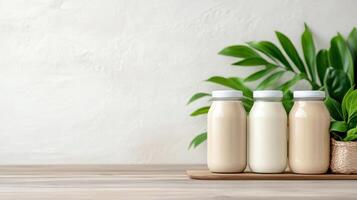 Three bottles of milk and a plant on a wooden table photo