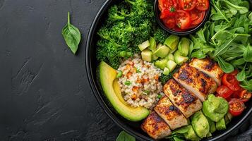 A bowl of food with chicken, rice, vegetables and avocado photo