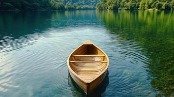 A wooden boat floating on the water in front of a forest photo