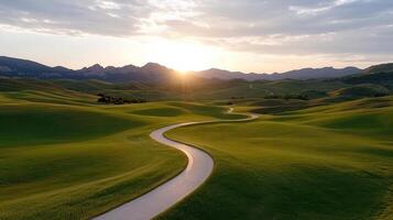 A winding road in a green field with mountains in the background photo