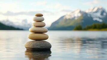 A stack of stones in the water with mountains in the background photo