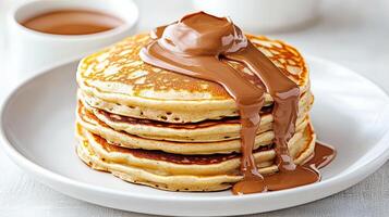 A stack of pancakes with chocolate syrup and a cup of coffee photo