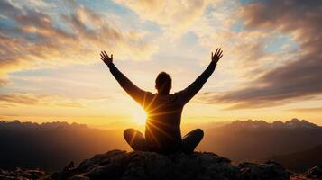 A person sitting on top of a mountain with their hands up in the air photo