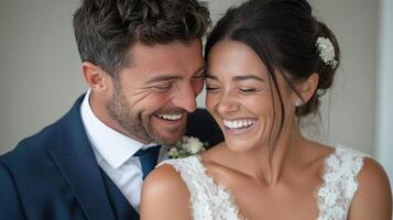 A bride and groom smile together in front of a window photo