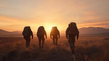 Three men with backpacks walking in the desert at sunset photo