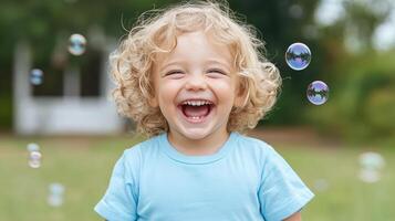 A young child is laughing while bubbles float around him photo