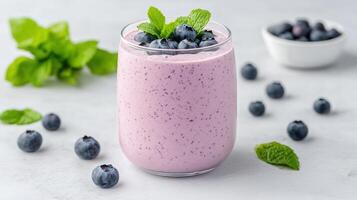 Blueberry smoothie in a glass with mint leaves and blueberries on a white background photo
