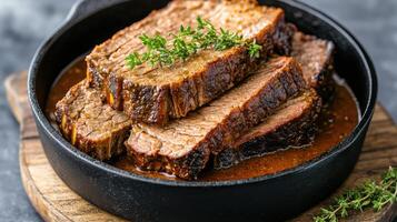 A piece of meat in a black skillet with a sprig of thyme photo
