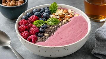 A bowl of smoothie with berries, nuts and a spoon photo