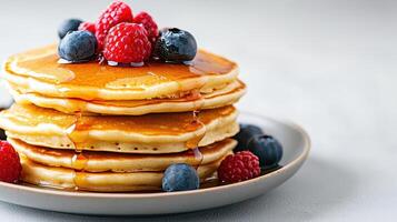 A stack of pancakes with berries and syrup photo
