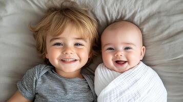 Two young children are smiling and laying on a bed photo