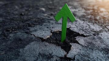 green arrow symbolizes growth emerging from cracked ground, representing resilience and hope photo