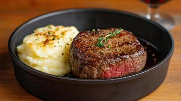 A steak and mashed potatoes in a black bowl photo