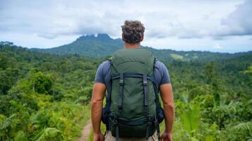 Man with backpack standing on trail in jungle photo