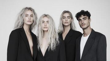 Four models in black suits posing for a photo