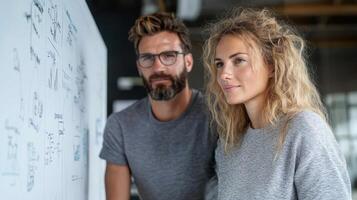 A man and woman standing in front of a whiteboard photo