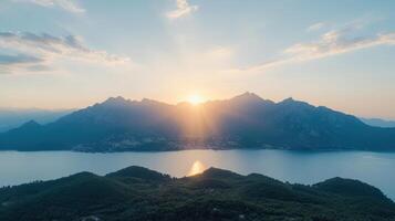The sun rises over the mountains and lake in this aerial photo