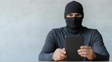 A man in a black mask holding a tablet photo
